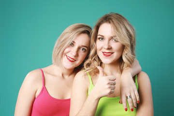 Two caucasian girls twins smiling,showing like over green background.