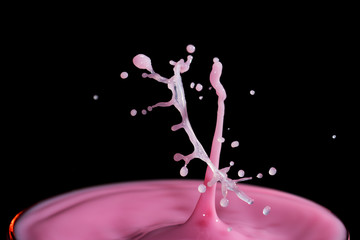 Water droplet hitting the surface of a glass of Milk isolated over black background