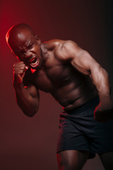 Vertical photo Muscular fighter frenchman standing in a boxing pose doing a punch towards the camera in red light.