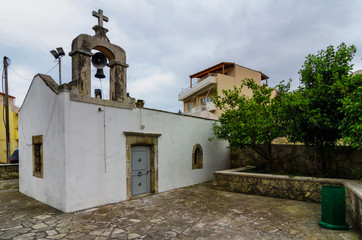 Fototapeta premium The Saint Catherine (Agia Ekaterini) greek - orthodox old chapel with it's paved backyard in Archanes town, Heraklion prefecture, Crete island - Greece. Afternoon time with cloudy sky