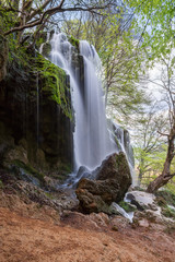 Naklejka na ściany i meble Beautiful waterfall among rocks in spring time
