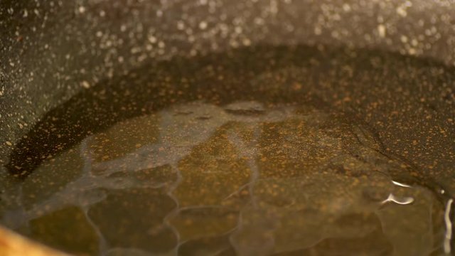 pouring cooking oil onto hot frying pan closeup