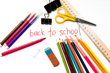 School stuff on a white background close up: colour pencils, scissors, eraser, colored markers, ruler