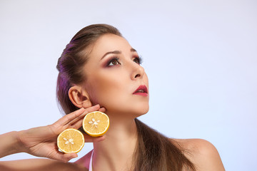 Beautiful girl with lemon isolated on light studio background. Fashion food photography, space for text. Cosmetology