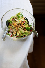 salad in a transparent bowl of avocado, walnuts, green salad, radish French mustard on a table with...