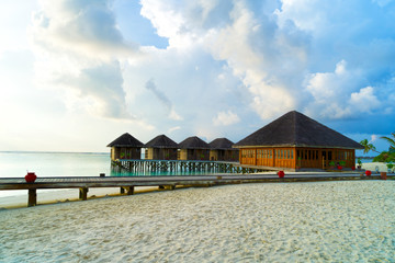 Wooden bridges leading to the huts on the shores of the tropical, warm sea. Maldives. Tourism concept.