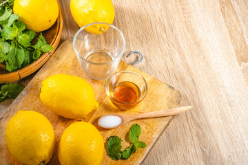 Freshly squeezed lemon juice and mint leave in clear glass cup on wooden chopping board and clean...