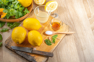 Freshly squeezed lemon juice and mint leave in clear glass cup on wooden chopping board and clean...