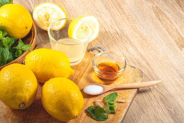 Freshly squeezed lemon juice and mint leave in clear glass cup on wooden chopping board and clean...