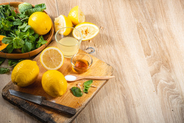 Freshly squeezed lemon juice and mint leave in clear glass cup on wooden chopping board and clean white marble background. Healthy Fruit juices that are high in vitamin C.