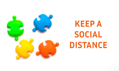 Multicolored puzzles and inscription KEEP A SOCIAL DISTANCE on a white background.Social distance concept to prevent the spread of coronavirus Covid-19.