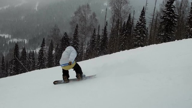 Slow motion of a male snowboarder jumping on a slope.