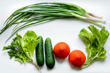 Fresh green vegetables and tomatoes on a white background