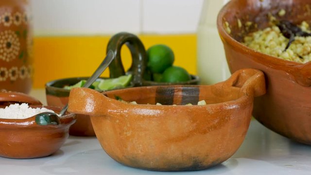 Woman hand's pours corn kernels and mayonnaise to prepare Mexican Street Corn Salad (Esquites) into traditional clay dish