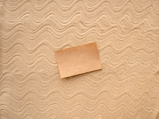 Letter in the sand. Craft paper for writing on patterned sea sand.