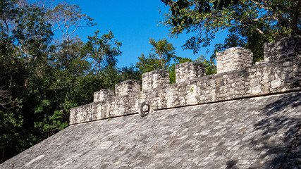 Mayan sport/games arena surrounded by tropical trees situated in Coba and made of stacked stones.