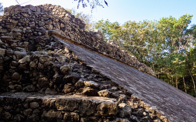 A Mayan sport arena made of stone under the shade of the tropical trees in Coba, Mexico.
