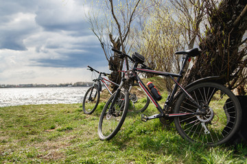 Fototapeta na wymiar Two mountain bikes stand on the river bank. Atmospheric dynamic light. Picnic.