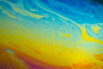 Abstract background blue-yellow iridescent waves. Soap bubble texture