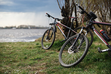 Two mountain bikes stand on the river bank. Atmospheric dynamic light. Picnic.