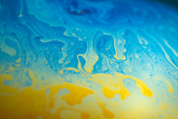 Abstract background blue-yellow iridescent waves. Soap bubble texture