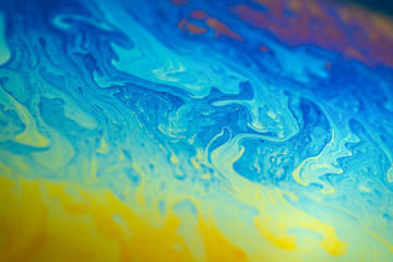Fototapeta na wymiar Abstract background blue-yellow iridescent waves. Soap bubble texture