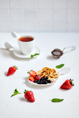 Mini-pancakes, Tiny pancakes, trendy food.
Fritters with fruit: blackcurrant, strawberry, mint. Breakfast with tea