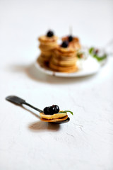 Mini-pancakes, Tiny pancakes, trendy food.
Fritters with fruit: blackcurrant, strawberry, mint. Breakfast with tea