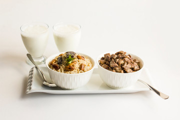 Traditional Turkish Islamic Feast,braised meat and rice in stylish white bowls on the white surface with fabric napkin and cold drink.