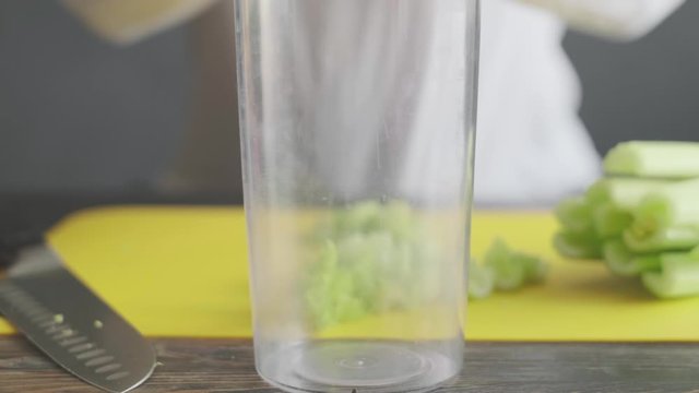 a woman prepares slices on a cutting board ingredients for a celery smoothie and puts them in a blender bowl