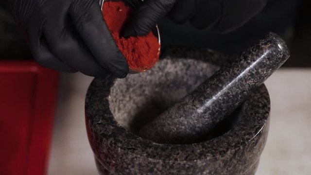 Chef pours spices into a mortar
