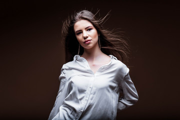 Beauty. Femininity. Beautiful female face with perfect genuine skin. Beauty salon. Make-up artist. Portrait of a beautiful woman in the studio. The girl inflates her hair. Girl in a white shirt. Face.