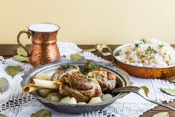 Lamb shank,rice and buttermilk drink,served on wooden table with handmade lace tablecloth and old vintage copper dishes.Traditional Islamic Feast or any holiday concept.