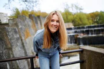 Beautiful portrait of a 90s redhead scandinavian teenager girl in jeans in a park near a lake © Максим Логвинов