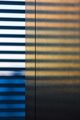 Sunlight streaming through blinds on wall at workplace