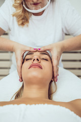 Beautiful and attractive adult woman receiving professional facial care beauty treatment with peeling mask.