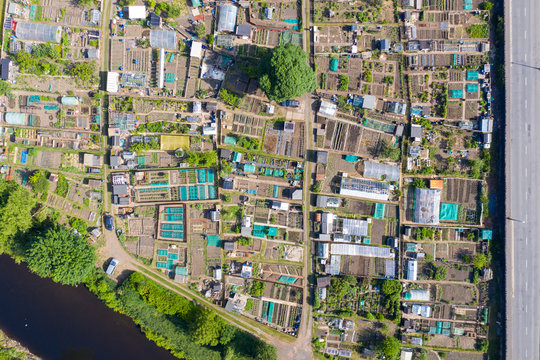 Top down aerial drone photo of the beautiful town of Mirfield in Kirklees, West Yorkshire, England showing a garden community allotment along side a river and public road