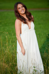 Stunning young Caucasian woman poses in white dressing field - summer fashion