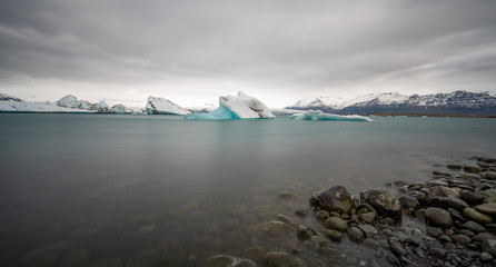 Long exposure panorama shot of melting crystal clear blue icebergs in Jokulsarlon glacier lagoon in Iceland.