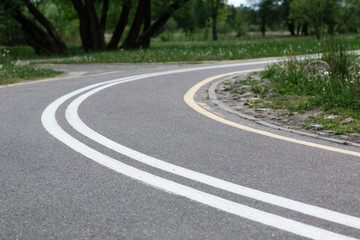 Turn of bike path in spring park. Empty road.