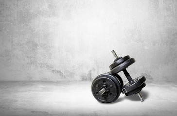 Dumbbells on a light background. The concept of sport and training, the weights lie on the ground. Black dumbbells ready for exercise, taking care of your figure and physical health.