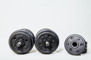 Dumbbells on a light background. The concept of sport and training, the weights lie on the ground. Black dumbbells ready for exercise, taking care of your figure and physical health.