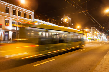 Naklejka na ściany i meble Motion blurry bus down the street in the evening.
