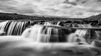 Closeup of waterfall cascades outdoors in landscape scenery in black and white.