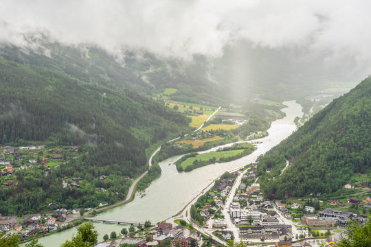 Otta city in Sel, Norway shot from above during rainy weather and sunbeams through low clouds.