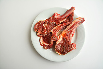 Lamb chops marinated with seasoning and ready for cook on white with copy space.
