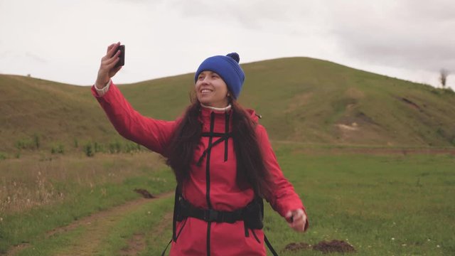 free Young girl tourist blogger records selfie videos at foot of mountains using a smartphone with beautiful landscape in background. Healthy cheerful woman travels and photography nature by phone