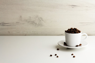 A cup is full of coffee beans on a light background