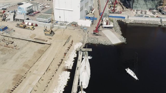 The big industrial crane lifts the sailboat and floats it, the beginning of a season of sailing, drone view point, port Hercules