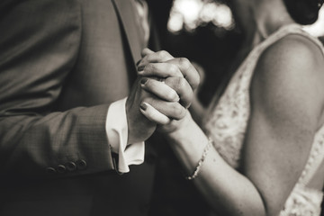 Black and white photo on dancing pair in formal clothes. Close up of holding hands. Shallow depth of field.